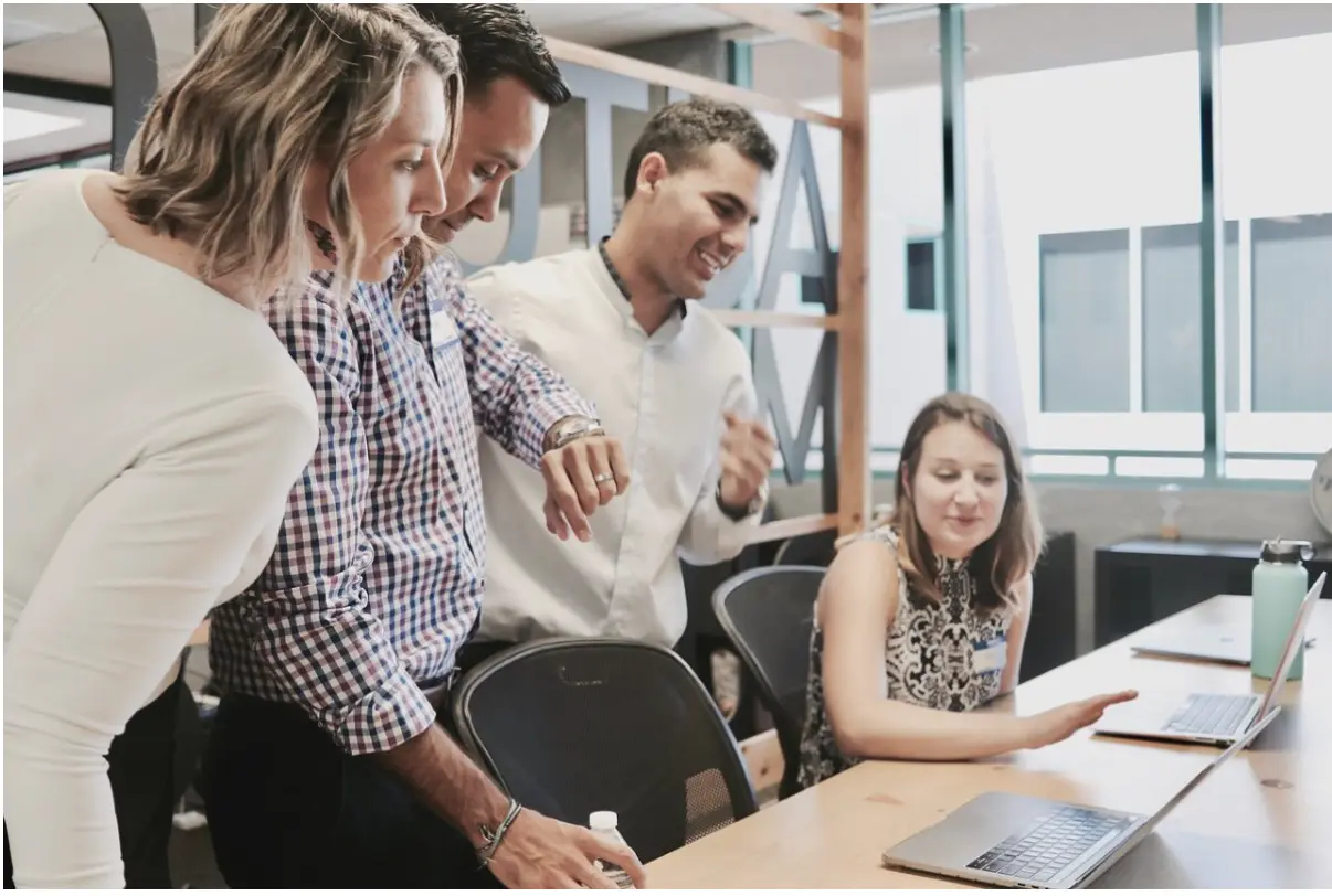 Men and Women looking at computer screen happily