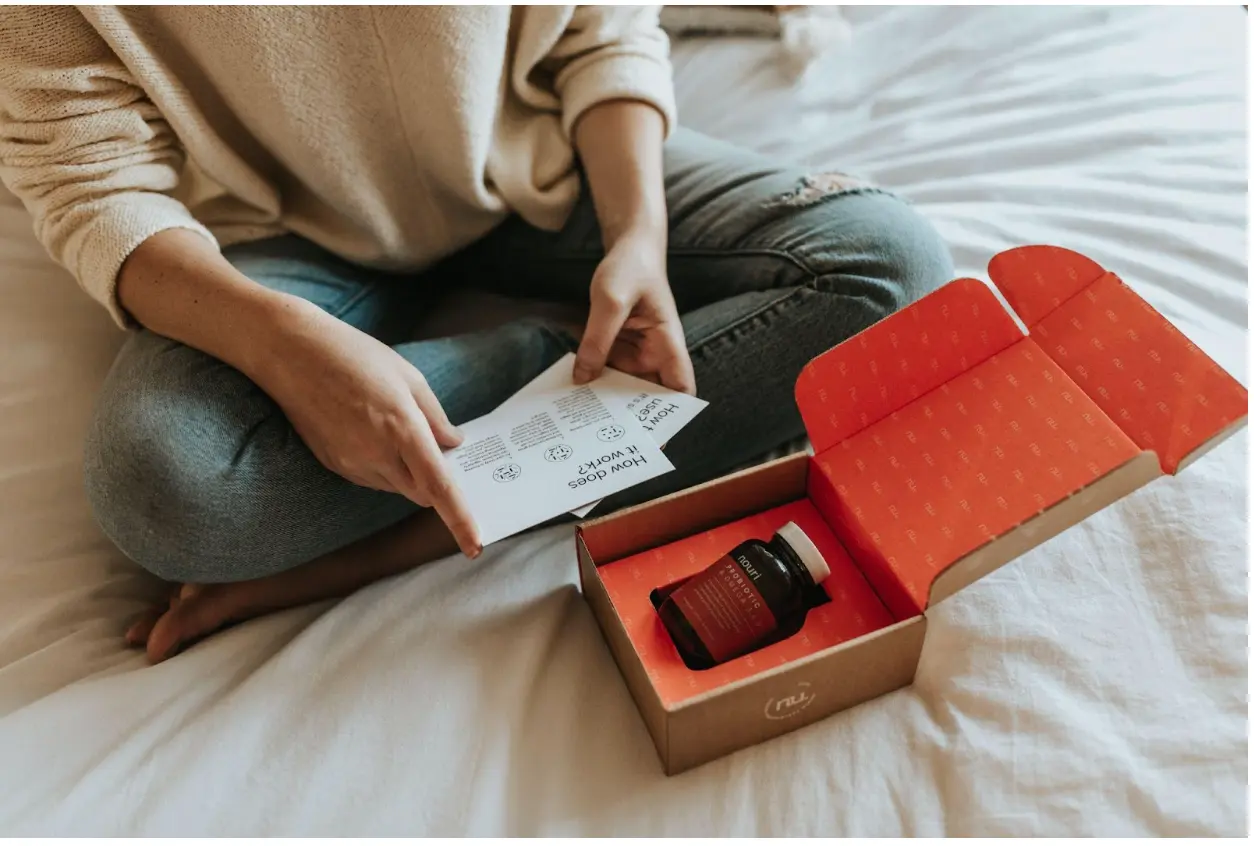 Woman sitting on bed while reading package materials