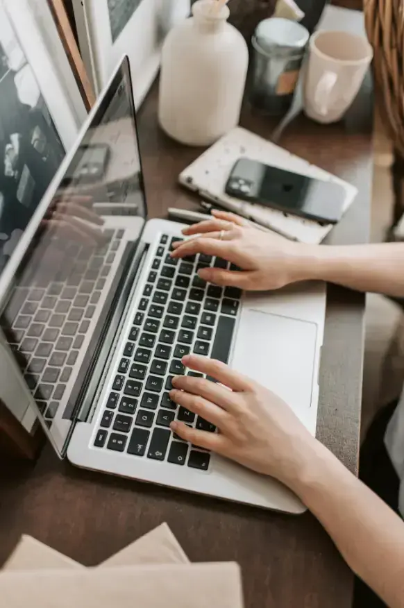 crop-female-freelancer-using-laptop-at-table-at-home