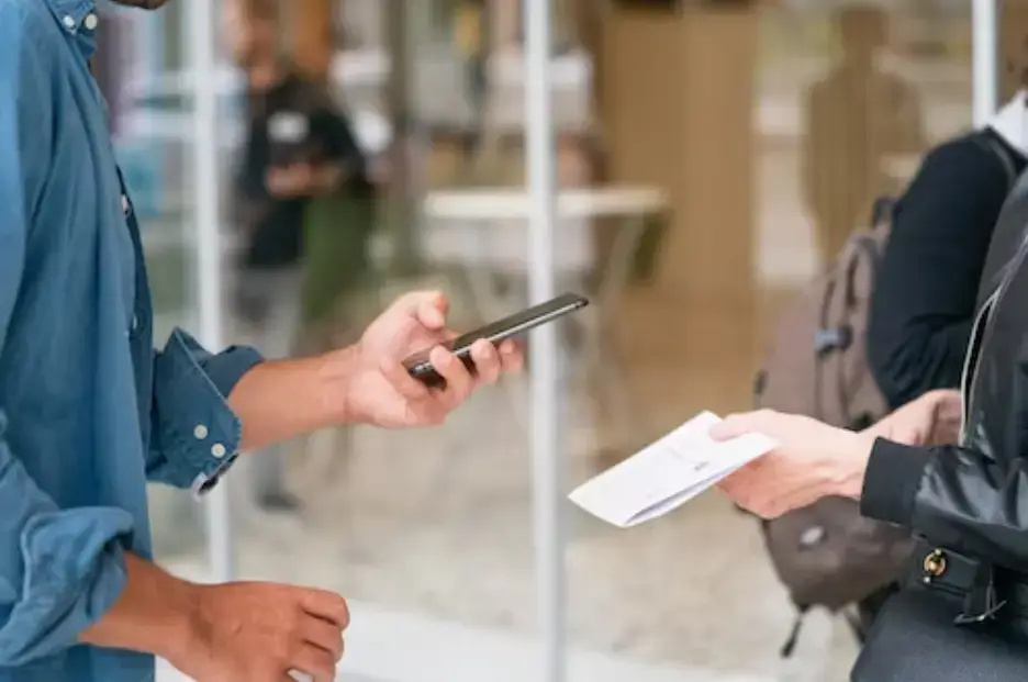 man-holding-smartphone-in-front-of-person-in-black-leather-jacket