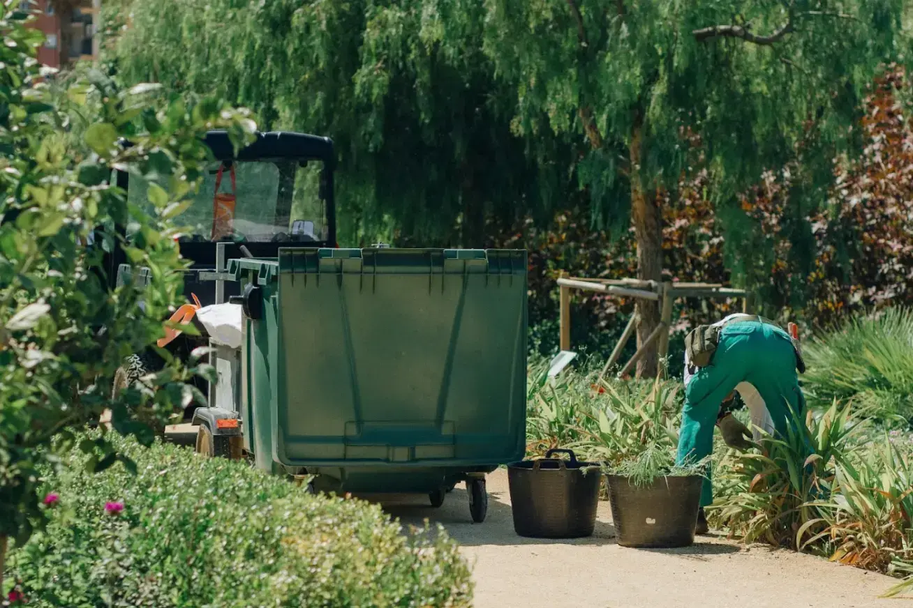 man-in-green-pants-near-the-garbage-cart