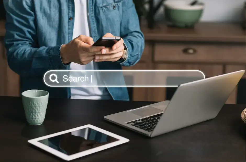 man-typing-on-his-smartphone-in-front-of-a-laptop