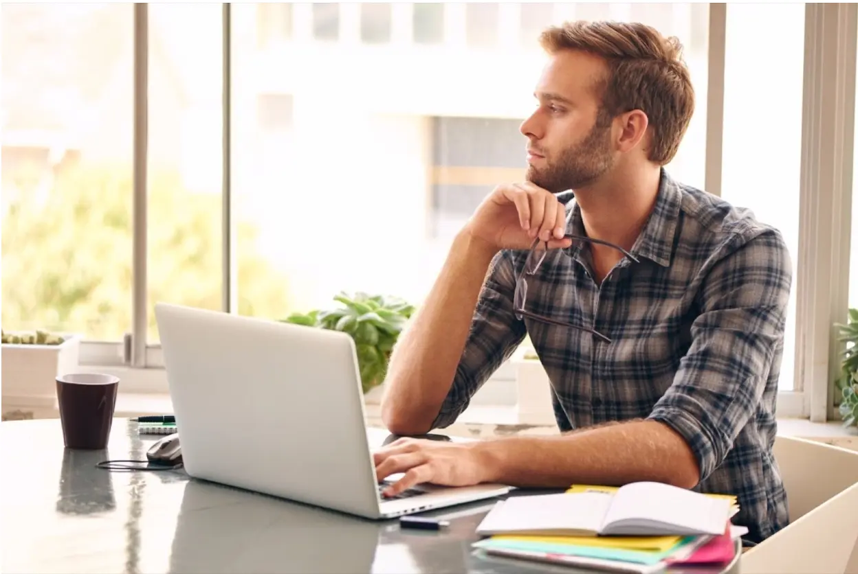 person thinking with his laptop in front