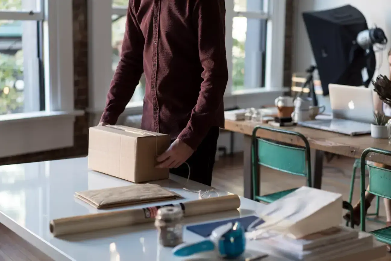 person-holding-cardboard-box-on-table