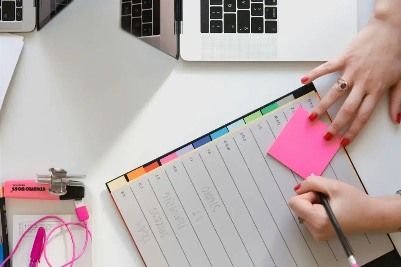 person-holding-pencil-and-stick-note-beside-table