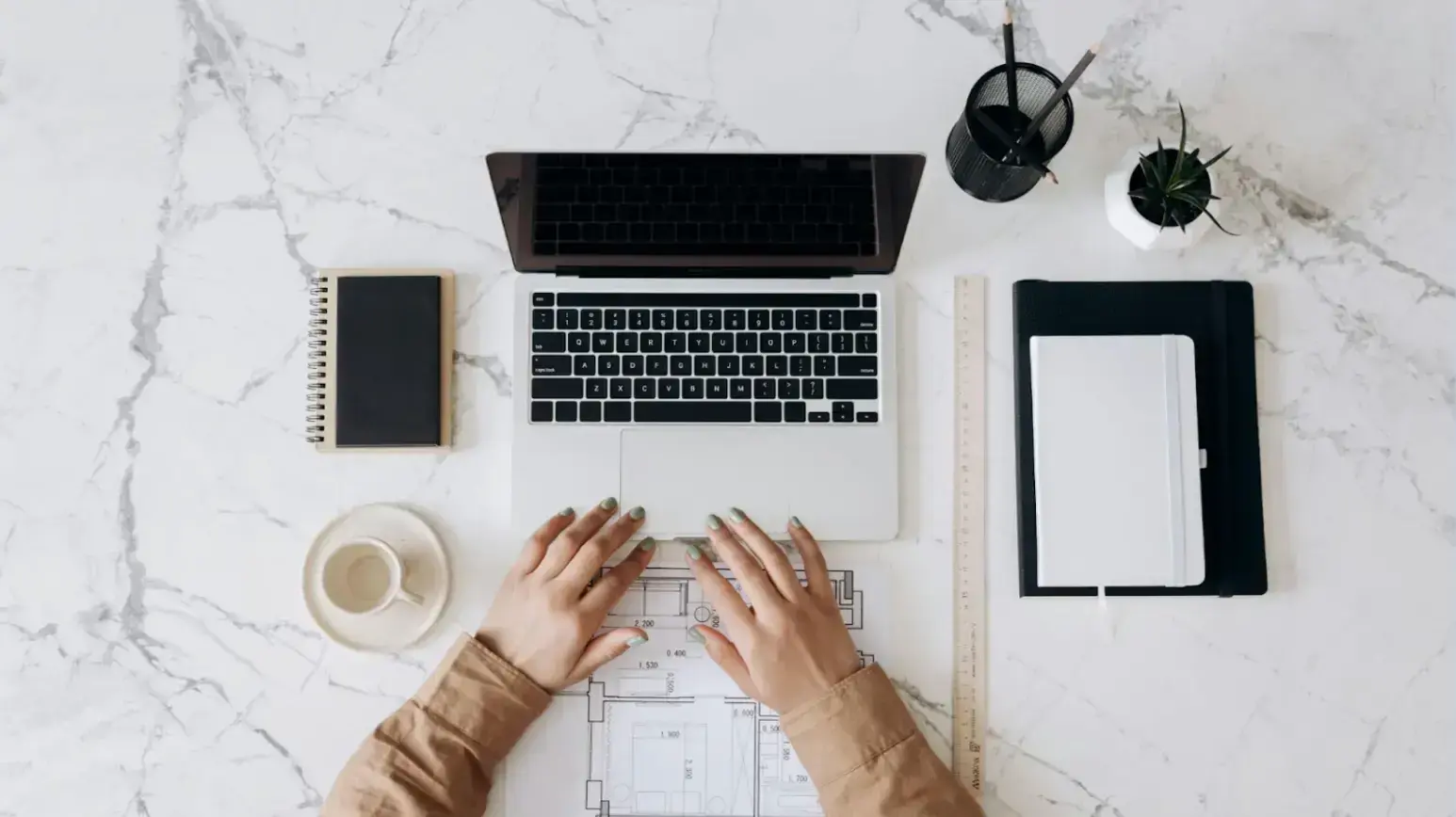 person-in-brown-long-sleeve-shirt-using-macbook-pro-beside-white-ceramic-mug