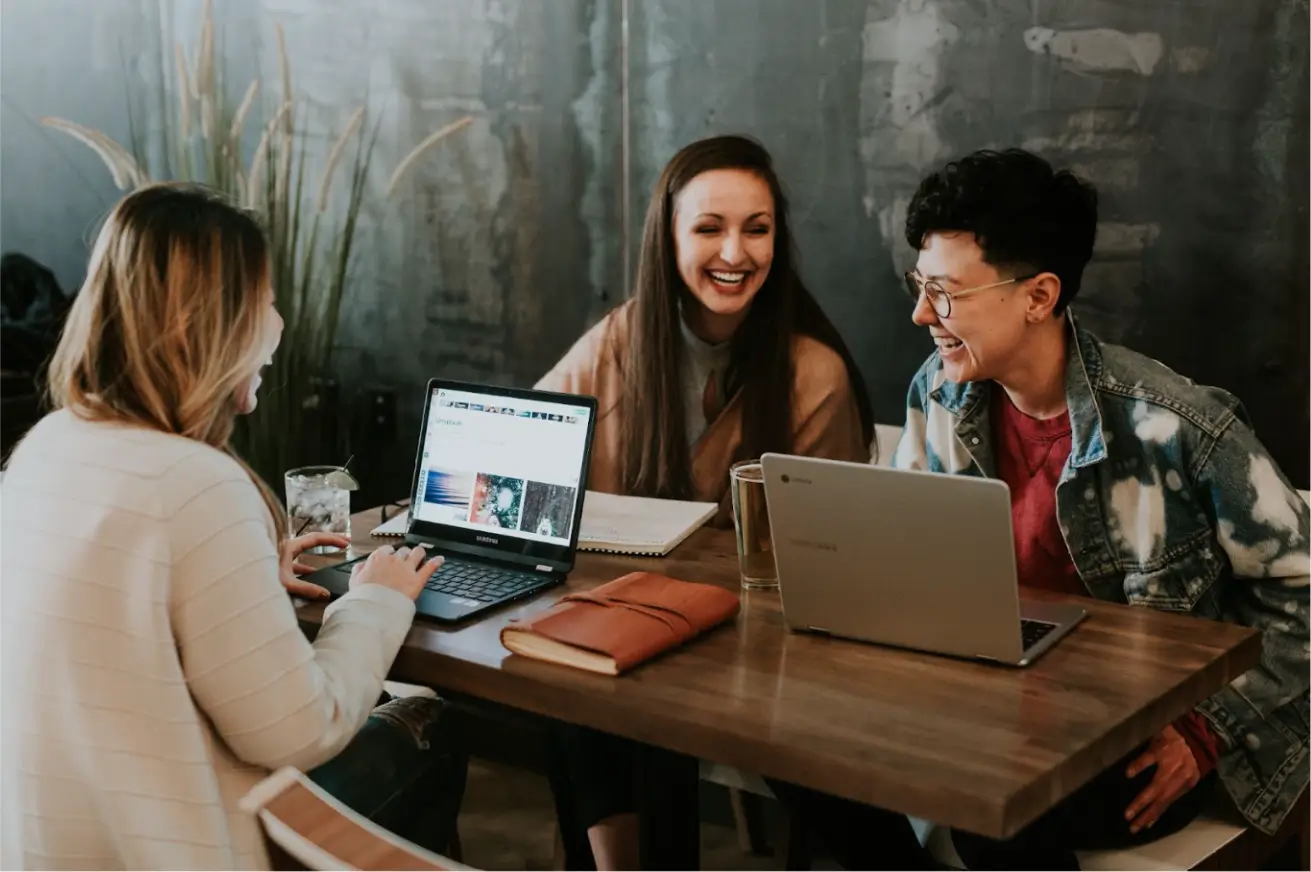 three-people-sitting-in-front-of-table-laughing-together