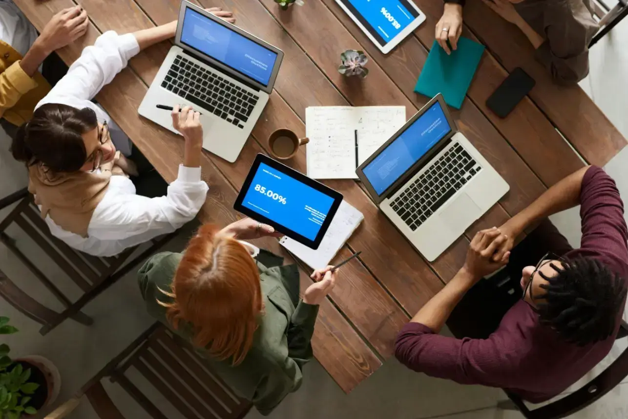 top-view-photo-of-group-of-people-using-macbook-while-discussing