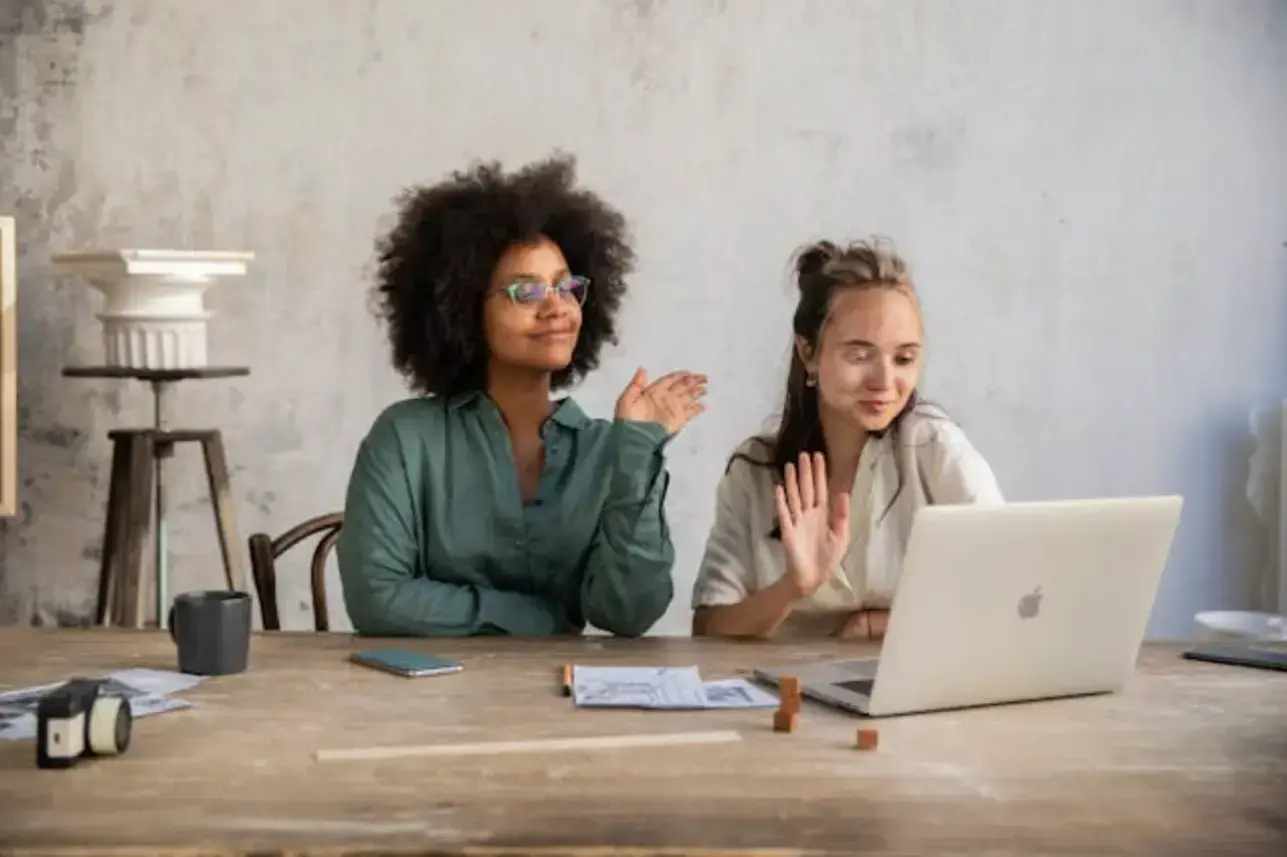 two-women-having-their-hands-while-looking-at-a-laptop