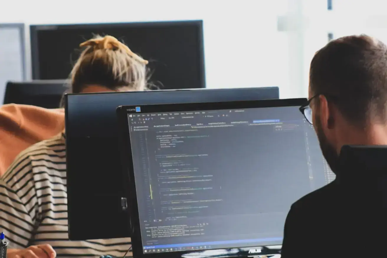 woman-in-black-shirt-sitting-beside-black-flat-screen-computer-monitor