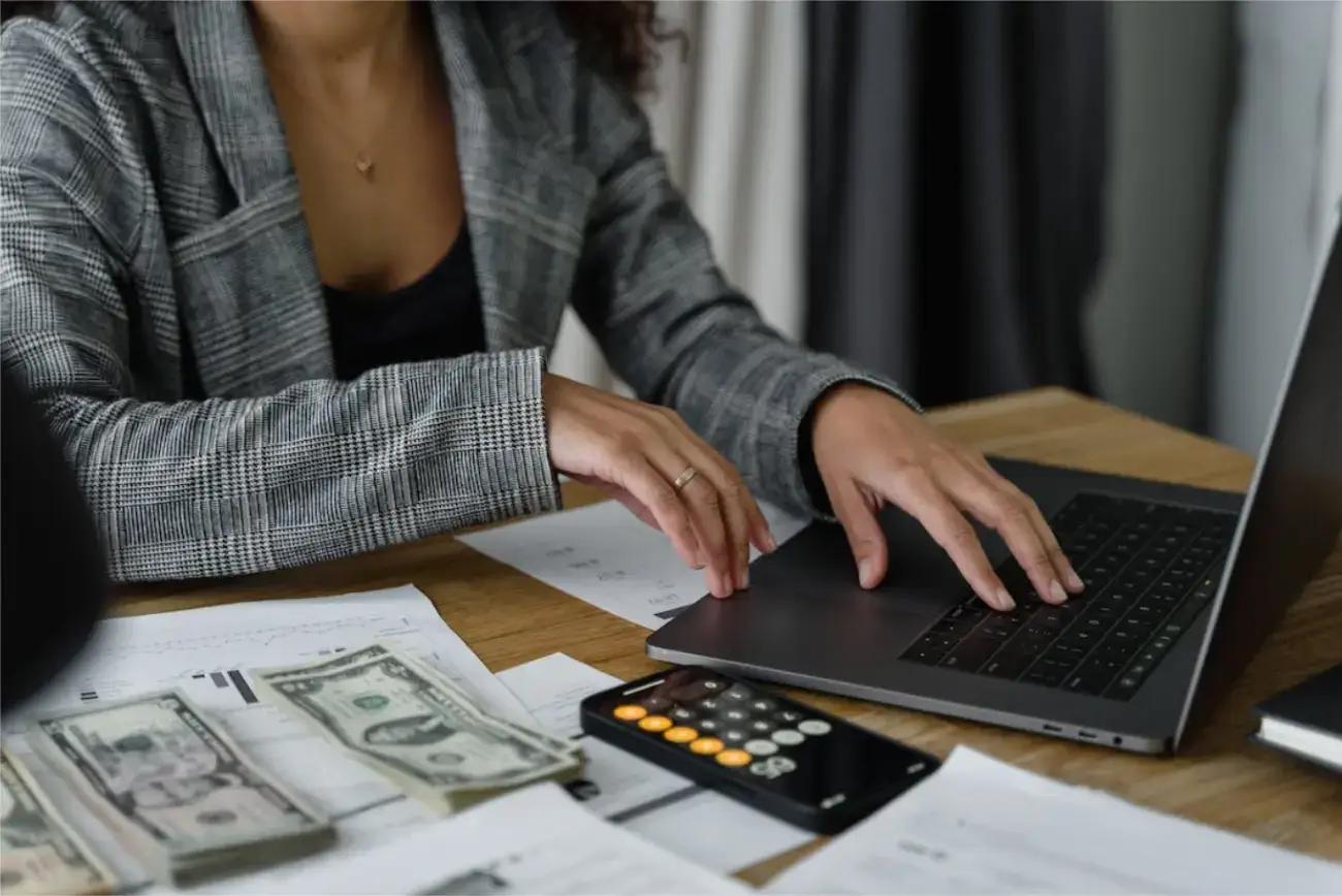 woman-in-front-of-laptop-and-near-piles-of-cash