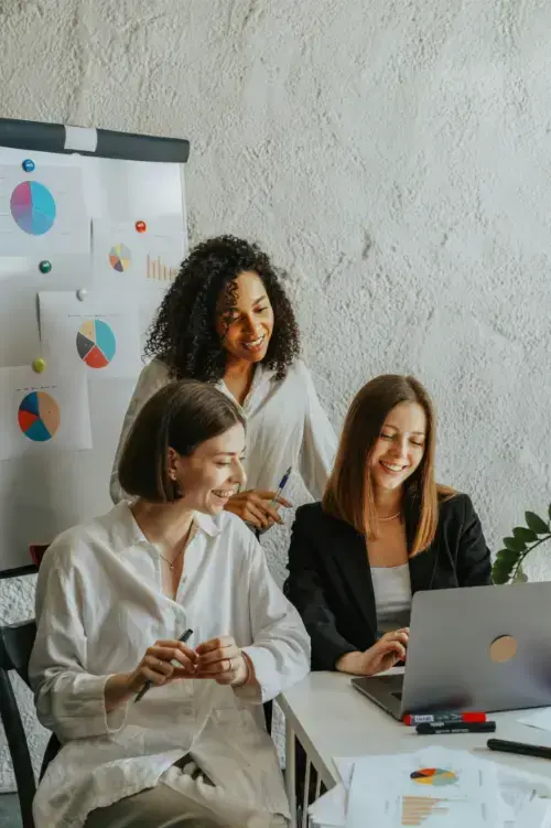 women-in-the-office-looking-at-laptop-screen-smiling