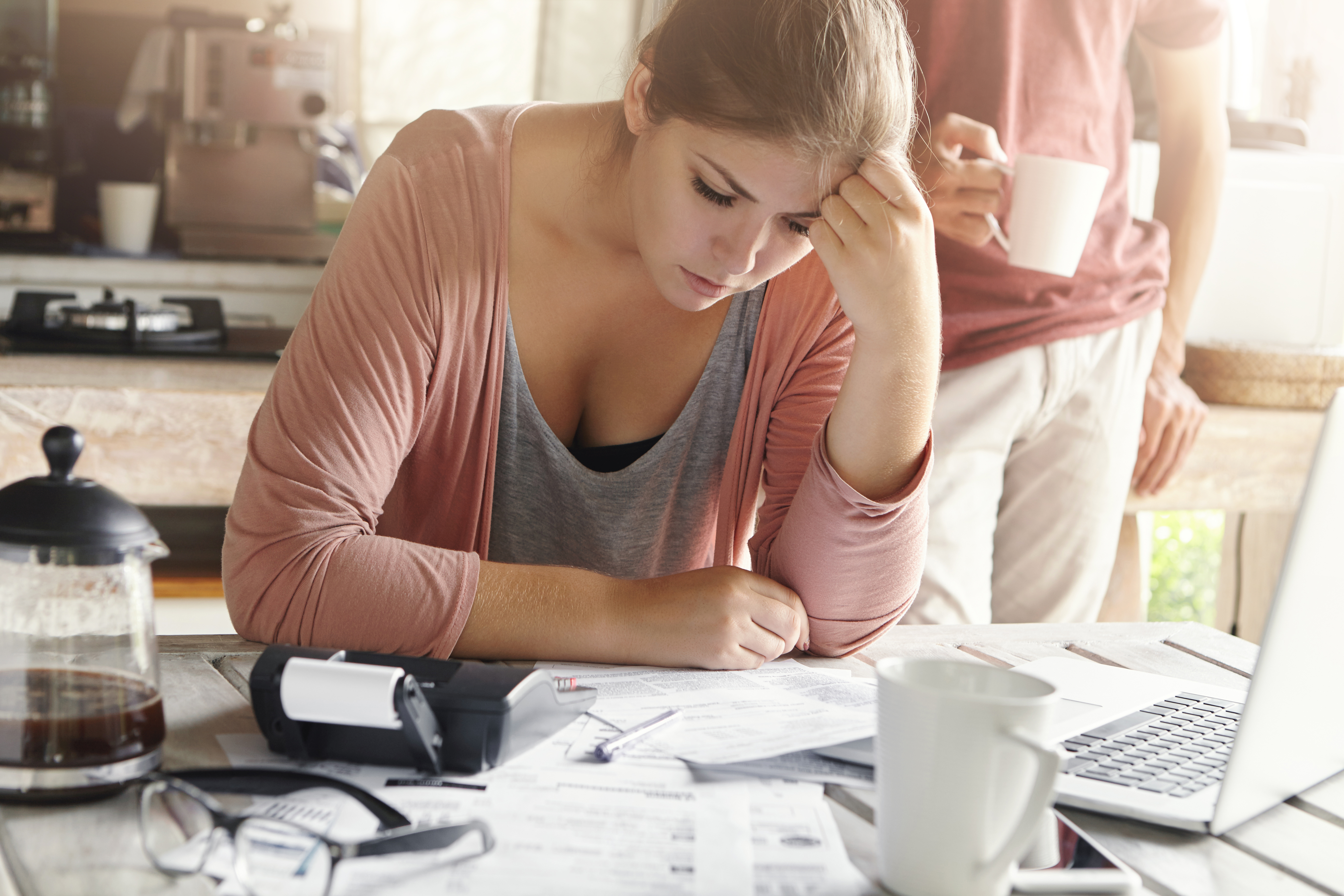 young-casual-female-having-depressed-look-while-managing-family-finances-doing-paperwork-sitting-kitchen-table-with-lots-papers-